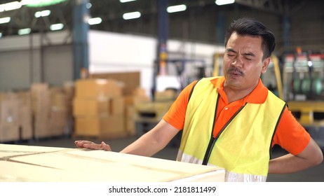 Asian man worker in a warehouse have an accident while carrying a heavy cardboard boxes with careless, male worker have a critical accident and injured at his back. - Powered by Shutterstock