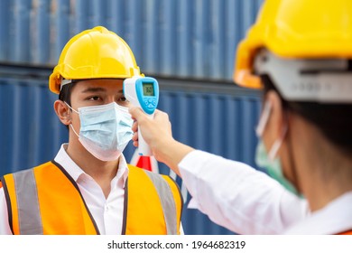 Asian Man Worker Wearing Face Mask Checking Fever By Digital Thermometer Before Entering The Work For Protecting From Covid, Covid-19 Or Coronavirus Pandemic On Construction Site. Selective Focus.
