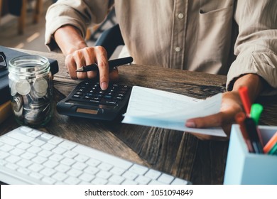 asiatischer Mann, der mit dem Rechner arbeitet, um Zahlen zu berechnen. Kostenrechner, Zahlungskosten mit Papierscheinen, Zahlungstabelle. Zahlungskonzept für Finanzdienstleistungen und Anlagen. Sparkonzept