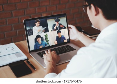 Asiatischer Hobbyarbeitnehmer nutzt intelligente Arbeits- und Videokonferenzen mit asiatischem Team und nutzt Laptop und Tablet online in Video-Call für neue Projekte