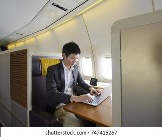 Asian Man Working With Laptop On First Class Airplane