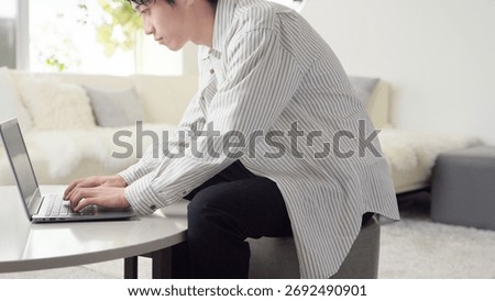 Asian man working on a computer with bad posture