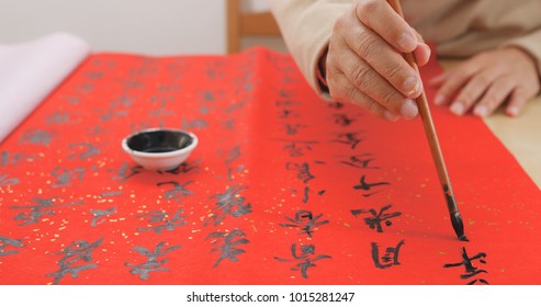 Asian Man Writing Chinese Calligraphy On Red Paper 