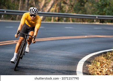 Asian Man In Yellow Cycling Jersey Riding On Road Bike With Willful Face.