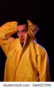 Asian man in a yellow suit of chemical protection on a colored trendy background. Fashion shooting in Asian style, neon lights and fashionable clothes, professional model. Coronavirus Protection.
