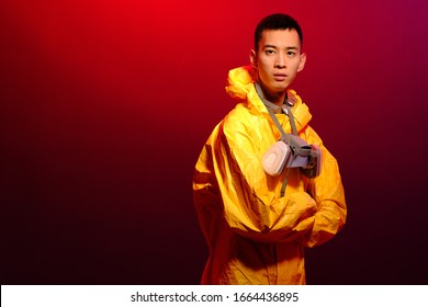Asian man in a yellow suit of chemical protection and in a protective mask on a colored trendy background. Concept Breaking Bad. The concept of the spread Epidemic of the coronavirus from China
