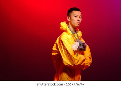 Asian man in a yellow suit of chemical protection and in a protective mask on a colored trendy background. Concept Breaking Bad. The concept of the spread Epidemic of the coronavirus from China