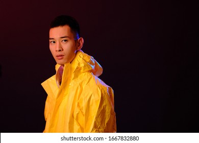 Asian man in a yellow suit of chemical protection on a colored trendy background. Fashion shooting in Asian style, neon lights and fashionable clothes, professional model. Coronavirus Protection.