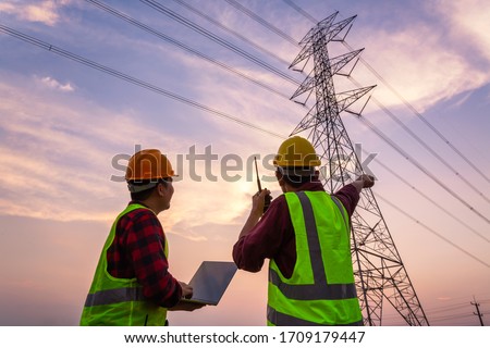 Asian Manager Engineering and worker in standard safety uniform working inspect the electricity high voltage pole.