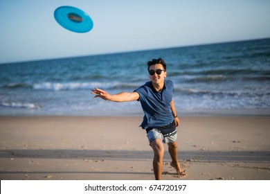 Asian manplaying frisbee  on the sea beach - Powered by Shutterstock