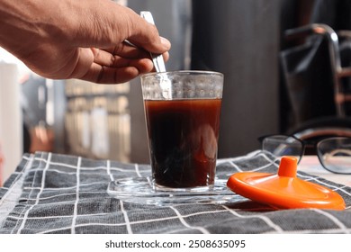 Asian man's hand stirs coffee with a spoon. Making coffee in the morning at home. Refreshing in the morning before going to work.  - Powered by Shutterstock