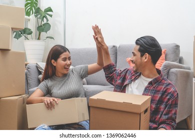 Asian Married Couple Start New Family Life Concept. Woman And Man Unpacking Messy Boxes After Moving In New House Together.