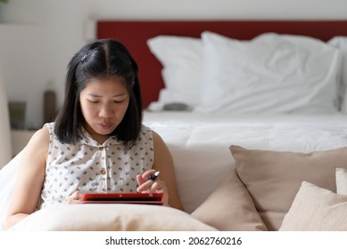 Asian Mature Adult Woking Remotely From Digital Tablet In Bedroom