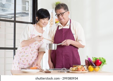 Asian Mature Couple Cooking Food At Kitchen. Seniors Living Lifestyle At Home.