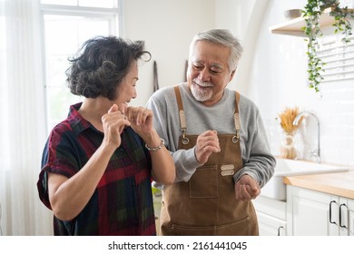 Asian mature senior couple is dancing and smiling in kitchen at home. - Powered by Shutterstock