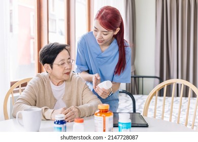 Asian Mature Senior Woman Holding A Medical Bottle And Asking For Information From The Nurse Before Administering Medication. Caregiver Visit At Home. Home Health Care And Nursing Home Concept.