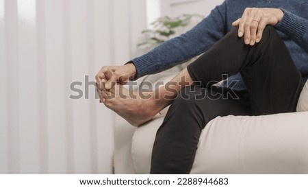 Asian mature woman feeling Foot Pain Leg of mature woman sitting on sofa
