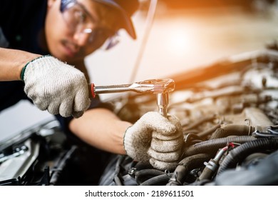 Asian Mechanic In A Car Repair Shop. Mechanic In Service Center Car Safety Check Repair Service Concept. Professional Service Concept. Close-up Photo
