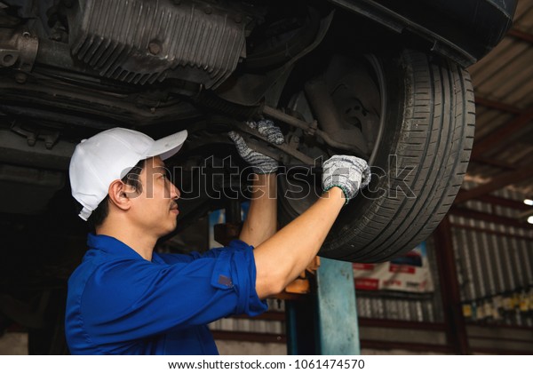 Asian mechanic looking under the car to repair the\
engine,japanese mechanic portrait style, mechanic maintenance\
working under car