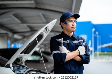 Asian Mechanic With Repair Equipment Standing Confidently In A Car Repair Shop. Auto Mechanic In The Service Center. Car Safety Inspection. Repair Service Concept.