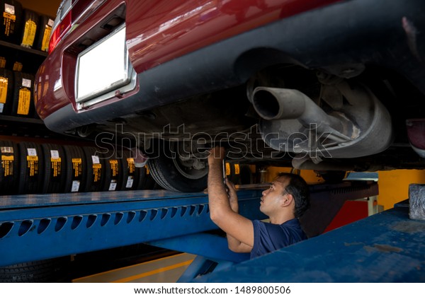 Asian\
Mechanic repairing a lifted car. Fixing car. Balancing the tire of\
the car. A car is lifting to let the Asian mechanic diagnostics the\
suspension of the vehicle to fix or repair\
it.