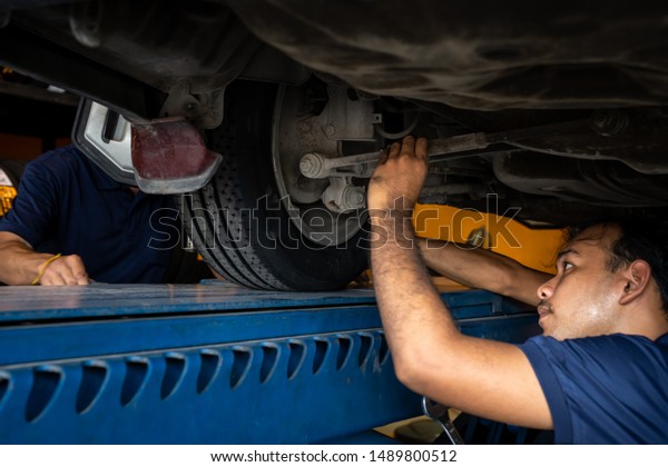 Asian
Mechanic repairing a lifted car. Fixing car. Balancing the tire of
the car. A car is lifting to let the Asian mechanic diagnostics the
suspension of the vehicle to fix or repair
it.