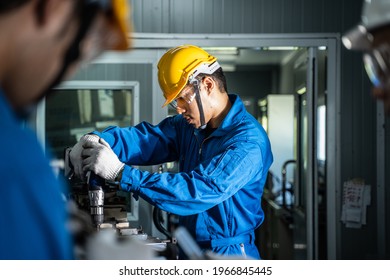 Asian mechanical workers working on milling machine. The technicians wearing protective glasses and helmet when operating the machine for safety precaution. Leader advising his team member doing a job - Powered by Shutterstock