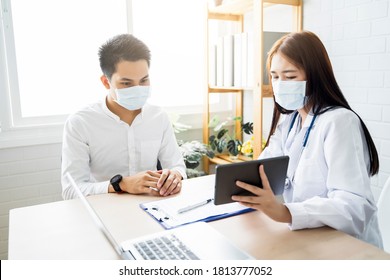 Asian Medical Healthcare Clinic Doctor Examining Diagnosing Male Patient Using Tablet Wearing Surgical Mask Protection Infection Disease, Working At Home Modern Office Technology Computer Laptop