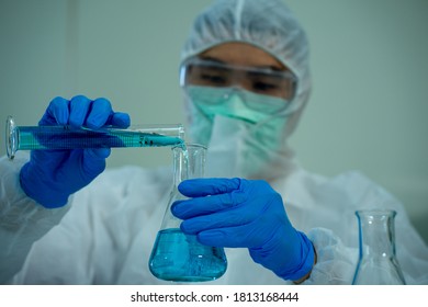 Asian Medical Scientist In Protective White Jumpsuit And Glasses And Face Mask Diagnosis Virus With Microscope In Clinical Laboratory