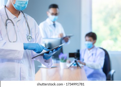 Asian Medical Team Wearing Medical Masks Technology Network Team Meeting Concept. Doctor At A Table Discussing A Patients Records Working, Online Medical Treatment, New Normal