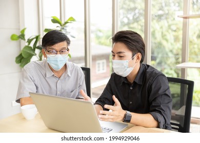 Asian Men 58 Years Old Wear A Mask And Talking Consultations With Insurance Agent And Using Laptop Computer In Home. Sell Insurance