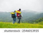 Asian men backpacker hiking on mountain hill in autumn. Healthy man traveler enjoy adventure outdoor active lifestyle hiking on nature trail mountain dirt road on holiday vacation. Ecotourism concept.