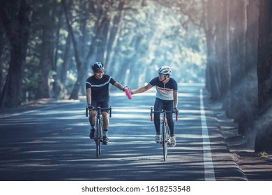 Asian men are cycling road bike in the morning and share out water to each other