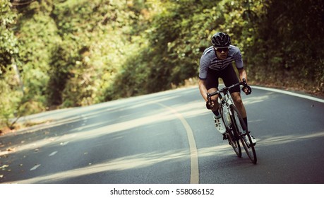 Los hombres asiáticos están en bicicleta por carretera por la mañana