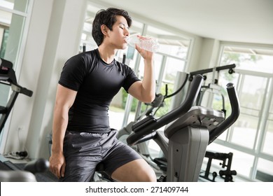 Asian Men Are Drinking Clean Water While Cycling Exercise At The Gym.