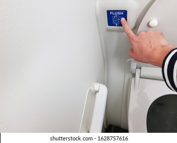 Asian men hand pressing blue flush button sign at the air plane lavatory to clean after use. Interior toilet design to match with small space inside the aircraft.  - Shutterstock ID 1628757616