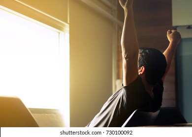 Asian men are holding their arms and fists to loosen their gaze out of the morning window, ready for the first day's work.