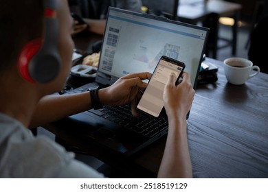 Asian men listen to music using a handset while conducting mobile banking transactions using a cell phone while working remotely at a cafe, concept of remote working, working flexibly from anywhere - Powered by Shutterstock