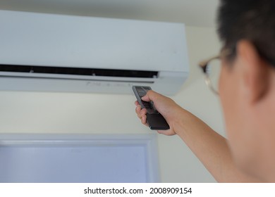 Asian men Use your hand to press the remote. to turn on the cooler in the house on a hot day. focus hand