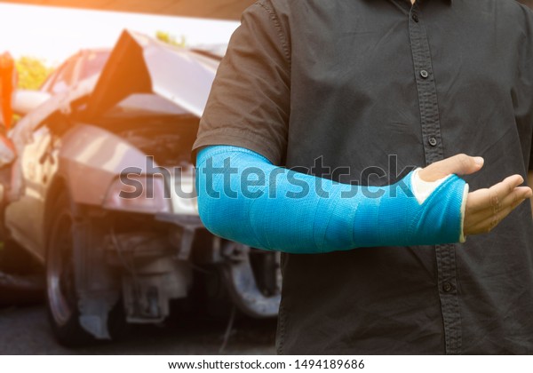 Asian men wear cloth splint on arm to treat car\
accident injuries.