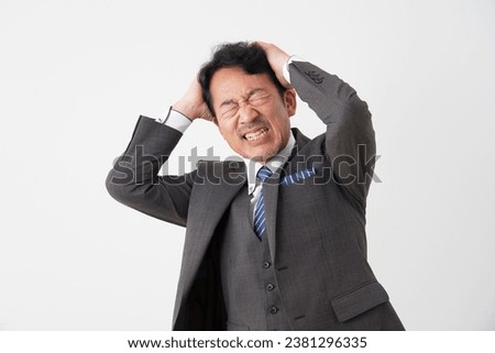 Asian middle aged businessman holding his head in white background