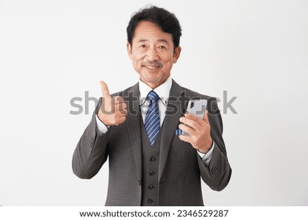 Asian middle aged businessman with the smartphone thumbs up gesture in white background