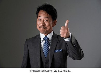 Asian middle aged businessman thumbs up gesture in black background