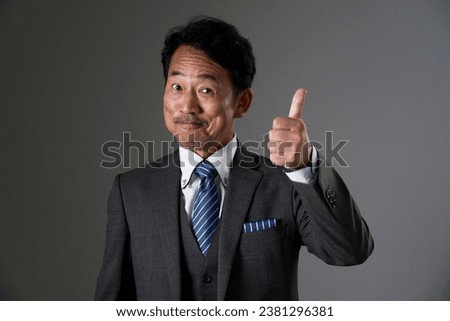Asian middle aged businessman thumbs up gesture in black background