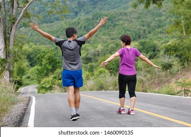 Asian Middle Aged Couple Stretching Muscles Before Jogging In Park