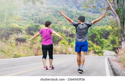 Asian Middle Aged Couple Stretching Muscles Before Jogging In Park