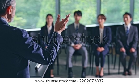 Asian middle aged man giving a lecture and audience.