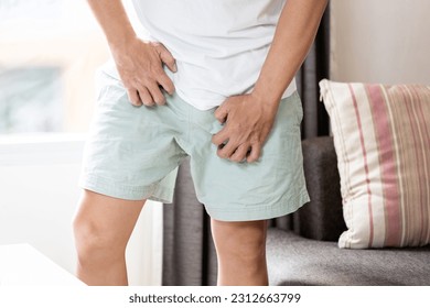 Asian middle aged man scratching crotch with his hand,itching groin area,pruritus,skin disease problem,Herpes simplex infection,male suffering from Tinea Cruris,jock itch,health care,hygiene concept