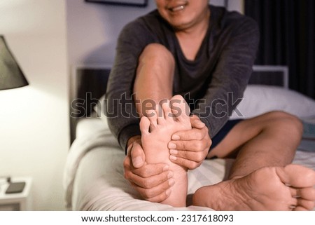 Asian middle aged man stretching leg,massaging sole of foot with his hands,muscles fatigue,sore in foot,plantar pain,stiffness in feet and heels,Plantar fasciitis,inflammation of the fascia of muscle
