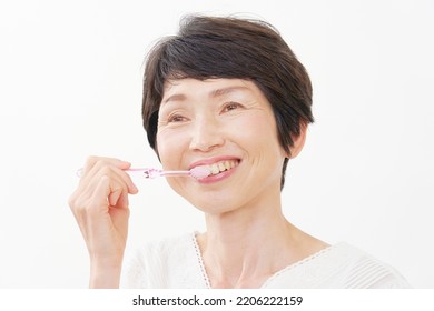 Asian Middle Aged Woman Brushing Her Teeth In White Background